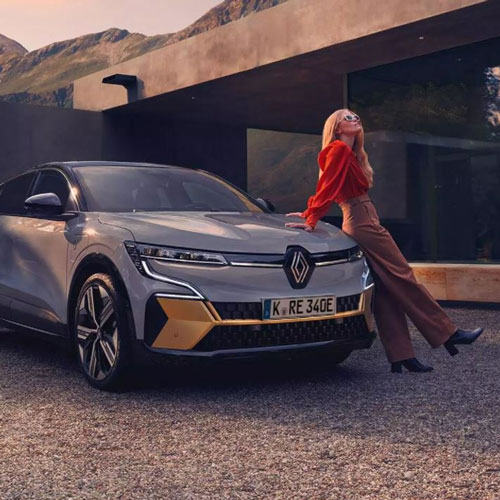 Zu sehen ist ein grauer Renault. Eine Frau lehnt sich an diesen.