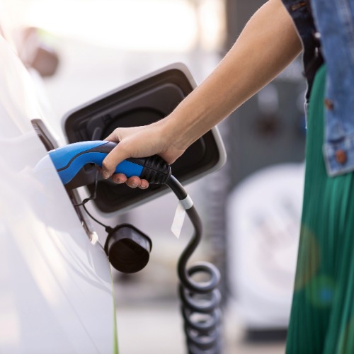 Frau lädt Elektroauto