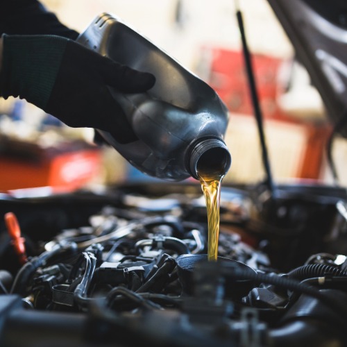 KFZ Mitarbeiter gießt Öl nach 