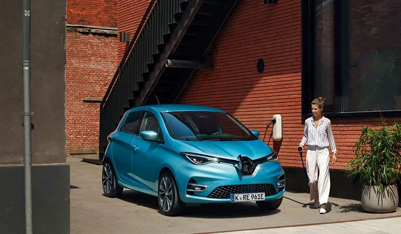 zu sehen ist eine Frau, die gerade dabei ist ihren blauen Renault Zoe zu laden